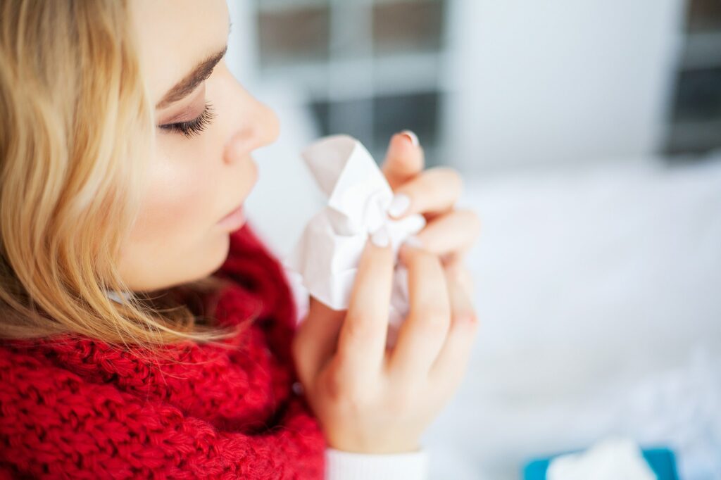 Sick woman with flu. Woman Suffering From Cold Lying In Bed With Tissue